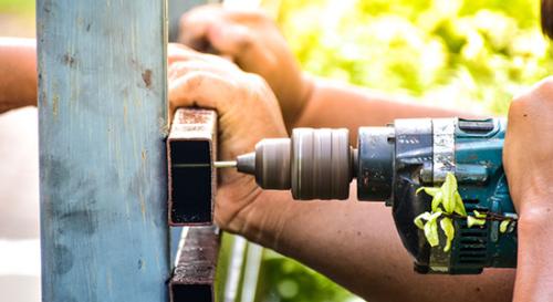 Closeup of using electric drill to fix a fence