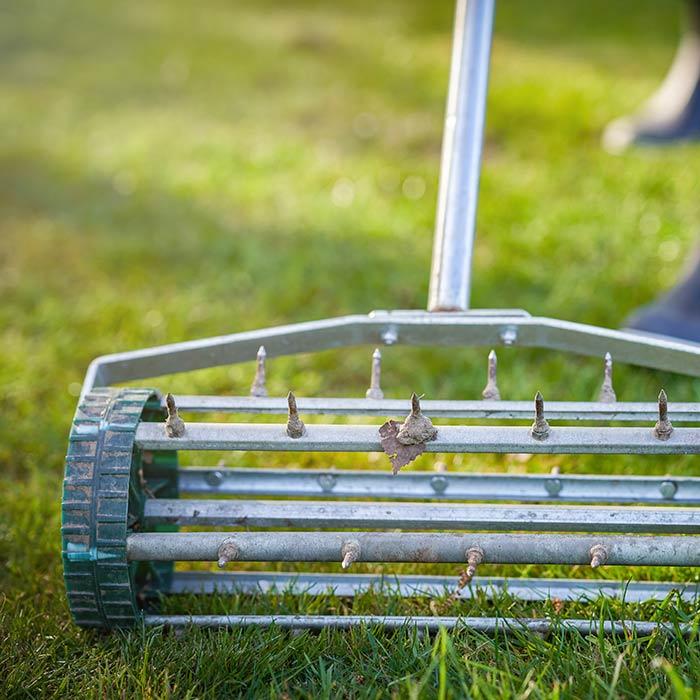 Closeup of manual lawn aerator on grass